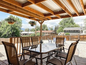 A covered patio with a table and chairs, surrounded by a wooden deck and a wooden fence. - 1422 Holmes (Colorado Springs)