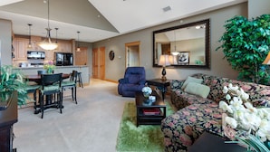 A spacious living room with a sofa, a dining area with a table and chairs, a kitchen in the background, and a ceiling fan. - RC 2050 309 (Coeur d'Alene)