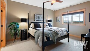 A bedroom with a four-poster bed, a ceiling fan, a large window with a view, and a potted plant. - RC 2050 309 (Coeur d'Alene)