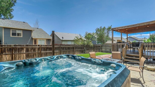 A backyard with a hot tub, wooden deck, and a covered patio area. - Hot Tub Retreat Near Fort Carson (Colorado Springs)