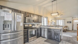 A modern kitchen with stainless steel appliances, a built-in oven, and a large island with a sink. - Hot Tub Retreat Near Fort Carson (Colorado Springs)