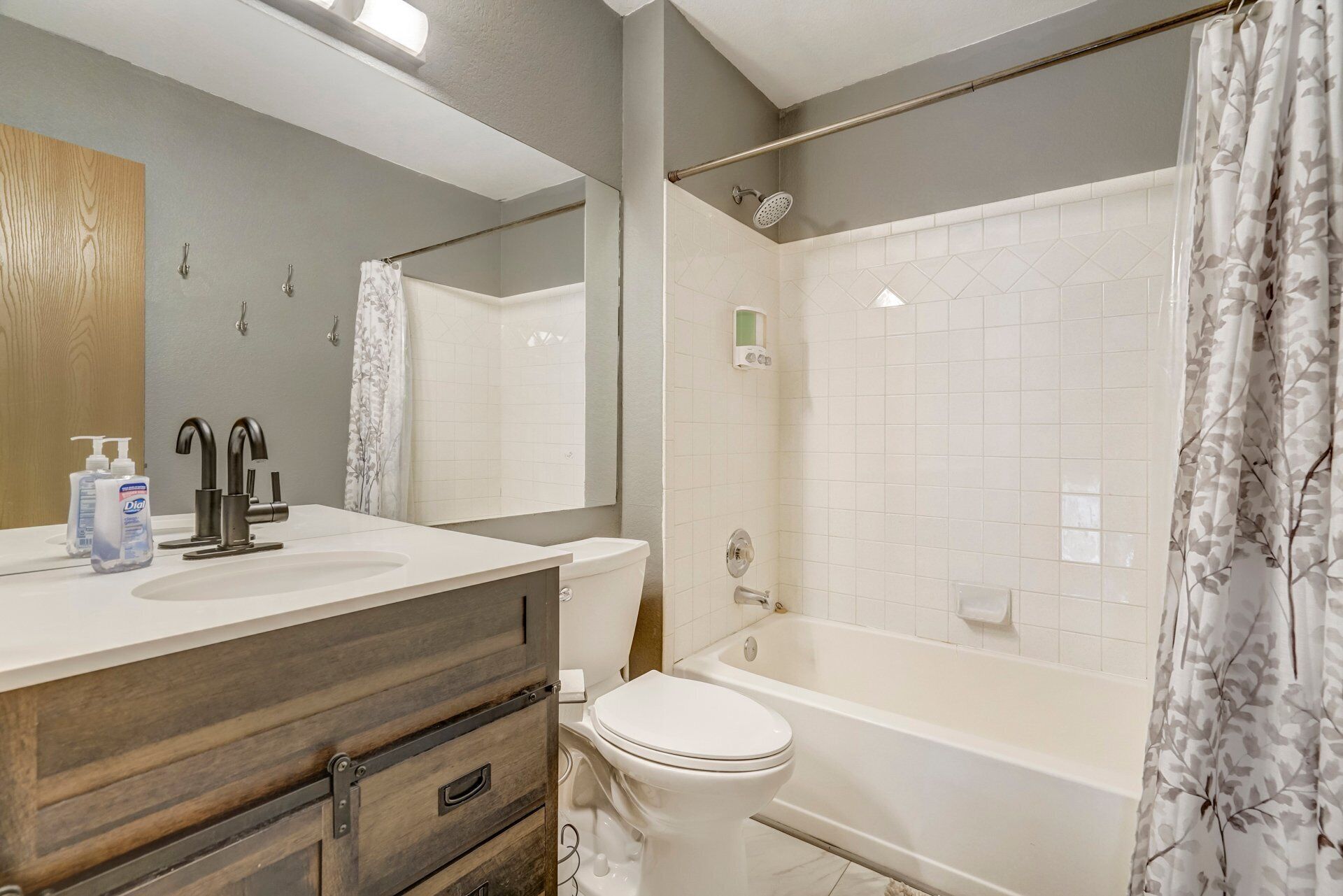 Een badkamer met een houten wastafel, een wit toilet, een bad en een douche met gordijn.