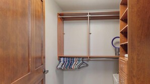 A walk-in closet with wooden shelving, a hanging rack, and a small mirror.