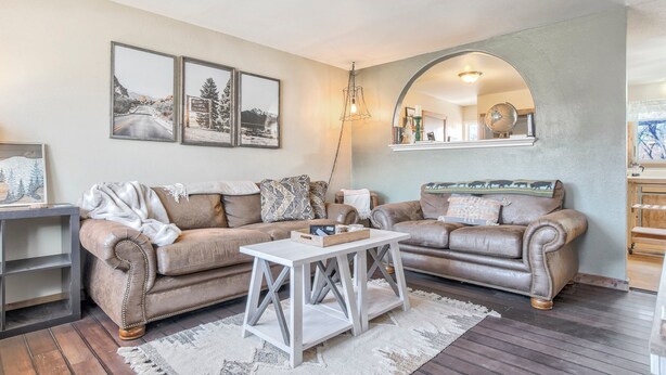 A living room with two brown leather sofas, a white coffee table, and framed pictures on the wall. - One Level Home Near Downtown Hot Tub (Colorado Springs)
