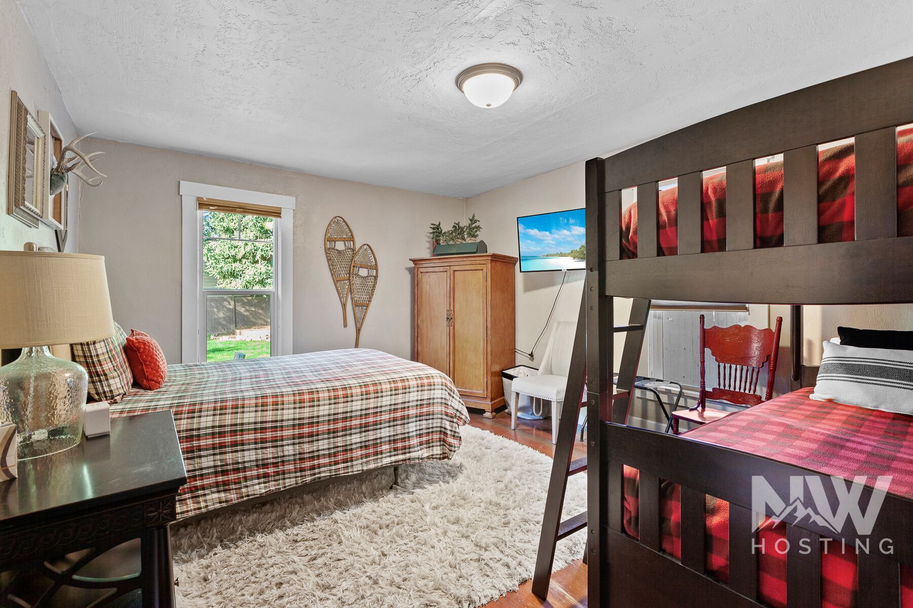 Quarto com cama, escrivaninha, cadeira, guarda-roupa e televisão.