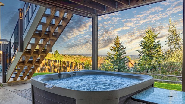 A hot tub with a wooden deck and a view of a wooden staircase and trees. - Mountain Retreat With Hot Tub & Views (Colorado Springs)