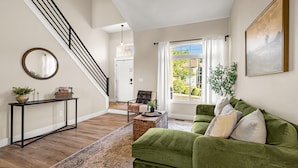 A living room with a green sofa, a round mirror, a console table, and a staircase. - Mountain Retreat With Hot Tub & Views (Colorado Springs)