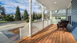 A wooden deck with a white railing, a table, and two chairs. - Downtown Getaway With Balcony King Beds (Colorado Springs)