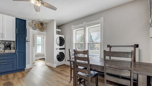 A kitchen with a coffee station, a dining area with a table and chairs, and a laundry room with two washing machines. - Downtown Getaway With Balcony King Beds (Colorado Springs)