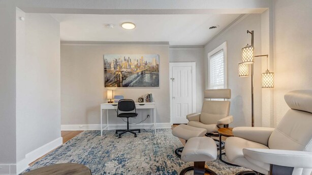 A modern living room with a desk, two chairs, a rug, and a painting on the wall. - Downtown Getaway With Balcony King Beds (Colorado Springs)