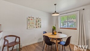 A dining area with a round wooden table, four chairs, a hanging pendant light, and two botanical posters on the wall. - Dt 01906 (Coeur d'Alene)