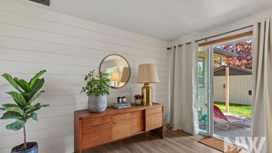 A room with a wooden desk, a potted plant, a mirror, a lamp, and a sliding glass door leading to an outdoor area. - Dt 01906 (Coeur d'Alene)