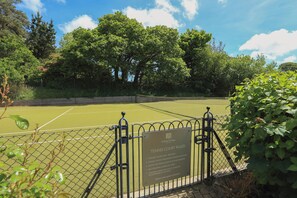 Tenniskenttä, jossa on kyltti, jossa kerrotaan kentän säännöt.