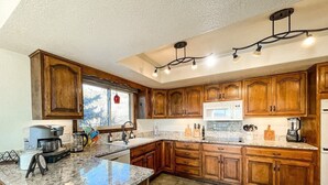 A kitchen with wooden cabinets, granite countertops, a built-in microwave, and a coffee maker. - Sunset Mesa Hideaway With Hot Tub (Colorado Springs)