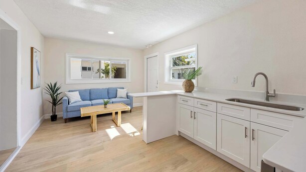 A modern kitchen with white cabinets, a blue sofa, and a wooden coffee table. - Welcome to The Drift Your Laid-back Beach Escape in Cocoa Beach! (Cocoa Beach)