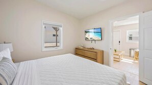 A bedroom with a bed, a dresser, a TV, and a window with a beach view. - Welcome to The Drift Your Laid-back Beach Escape in Cocoa Beach! (Cocoa Beach)