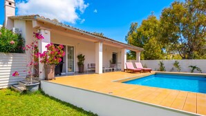 Una casa moderna con piscina, patio cubierto y jardín.