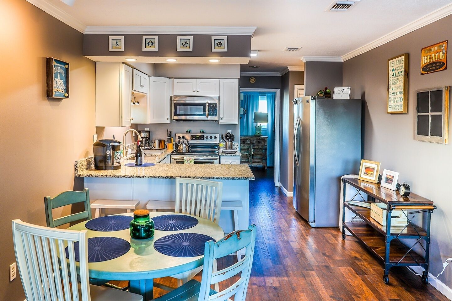 A modern kitchen with white cabinets, stainless steel appliances, and a dining area with a round table and chairs.