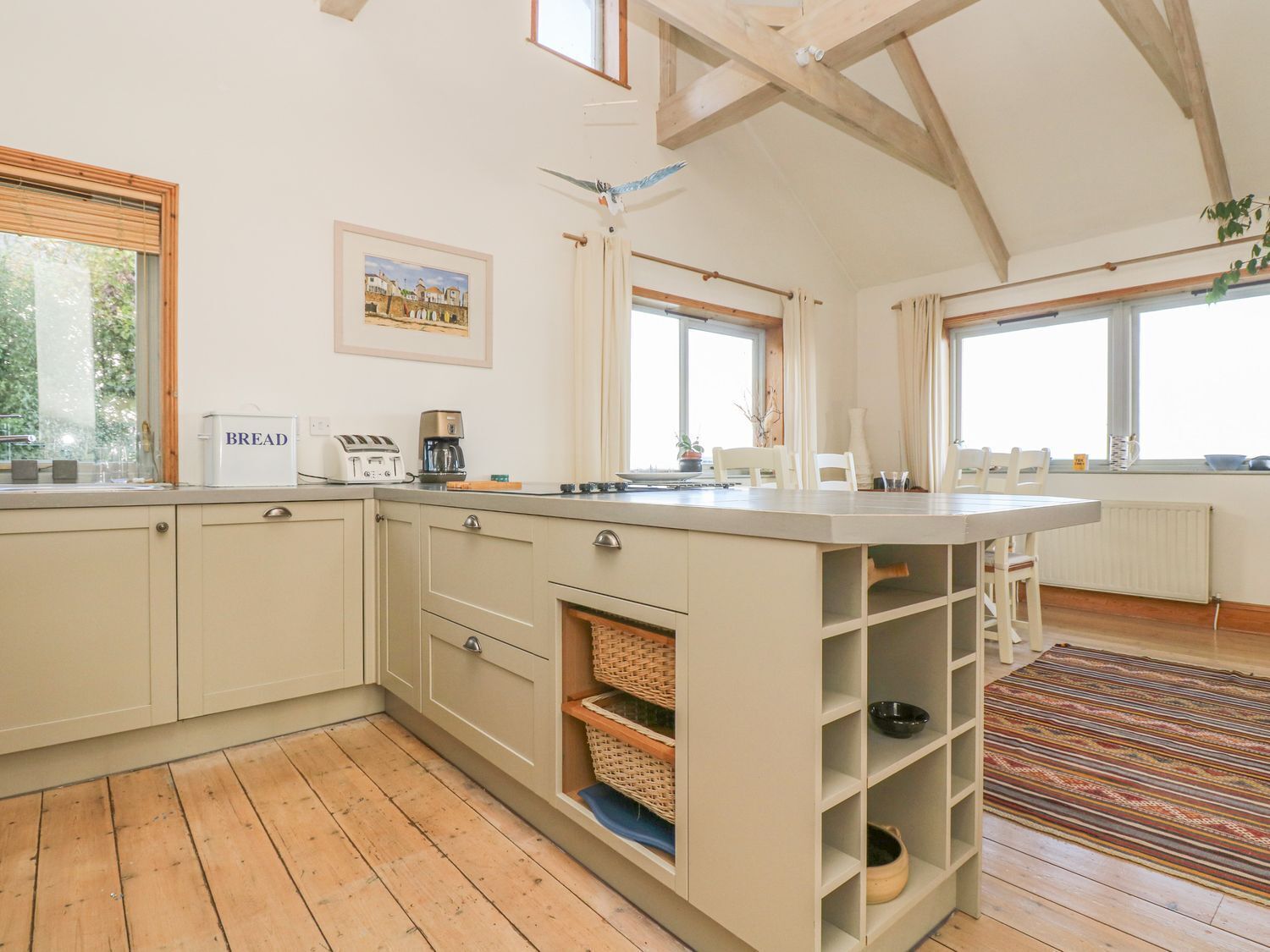 Une cuisine spacieuse avec un plancher en bois, un îlot central et de grandes fenêtres.