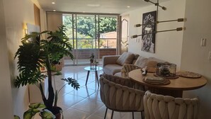 A modern living room with a sofa, dining table, chairs, and a large potted plant. - Your comfortable, elegant, and centrally located space with balcony 401 (Medellín)