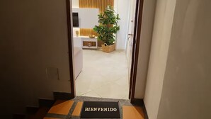 A hotel entrance with a 'BIENVENIDO' mat, a potted plant, and a reception area with a TV and decorative wall paneling. - Your comfortable, elegant, and centrally located space with balcony 401 (Medellín)