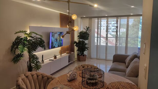 A modern living room with a sofa, a dining table, and large windows. - Your comfortable, elegant, and centrally located space with balcony 401 (Medellín)