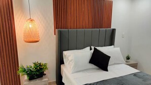 A modern bedroom with a bed, a nightstand, a potted plant, and a hanging light fixture. - Exclusive, luxurious, centrally located apartment — serene and comfortable 302 (Medellín)