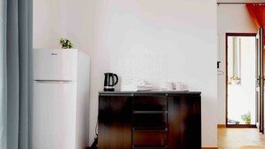 Een kleine keuken met een witte koelkast, een donker houten kast en een betegelde vloer.