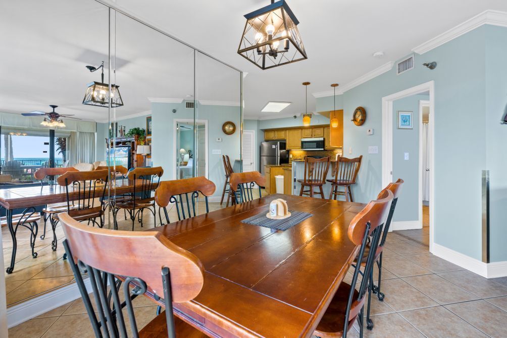 A dining area with a large wooden table, chairs, and pendant lighting.