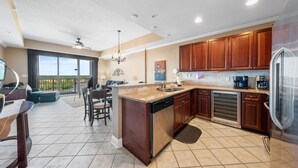 A modern kitchen with a large island, wooden cabinets, and a built-in dishwasher.