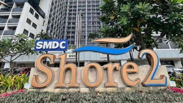 Um edifício moderno e alto com uma placa indicando 'SMDC Shore2'.