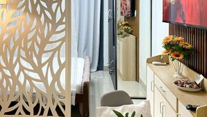 Quarto de hotel moderno com cama, escrivaninha, televisão e um painel decorativo.