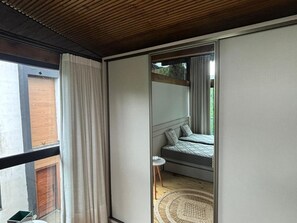 Um quarto com uma cama, uma mesinha e um tapete de fibras naturais.