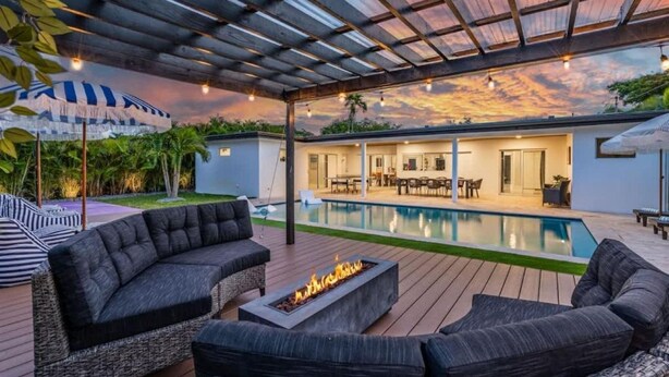 A covered outdoor area with a pool, lounge chairs, and a fire pit. - Villa Bonita Tropical Paradise Pool (Hollywood)