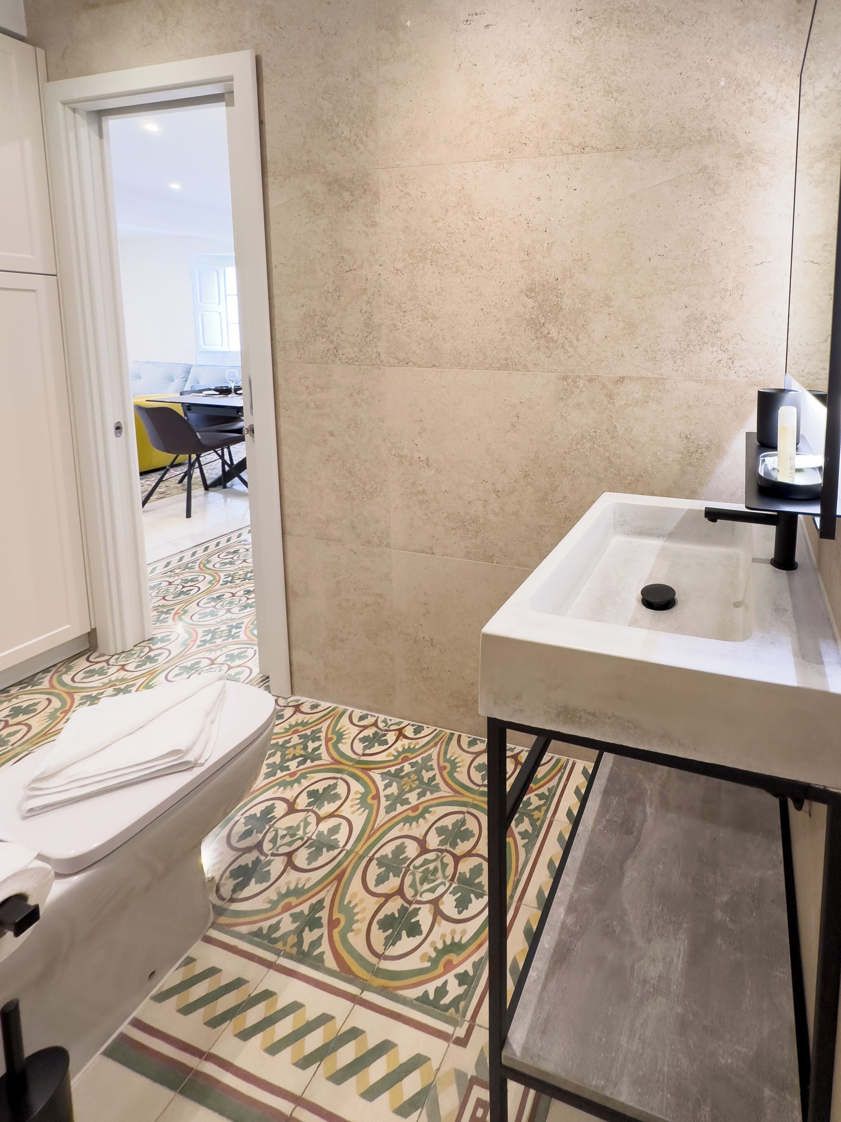Un baño con lavamanos, inodoro y baldosas de suelo estampadas.