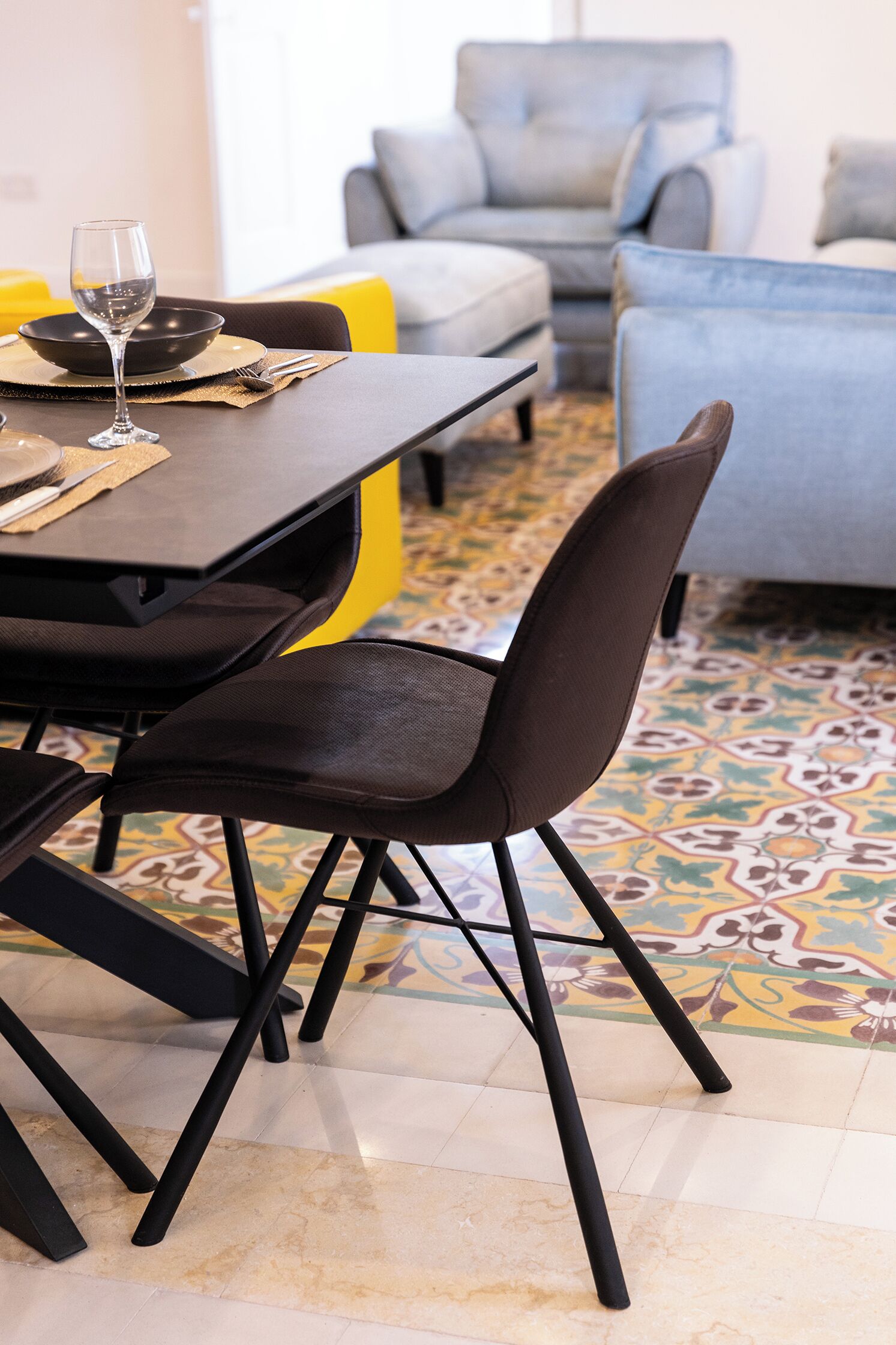 Une table à manger avec des chaises, un verre à vin et un bol.
