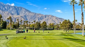 Ein Golfplatz mit Blick auf einen Berg, Palmen und einem klaren Himmel.
