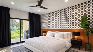 Ein Schlafzimmer mit einem großen Bett, einem Deckenventilator, einer Wand mit Muster und Blick ins Freie.