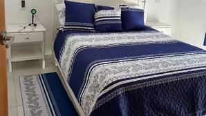 Un dormitorio ordenado con cama, mesita de noche y mesilla auxiliar.