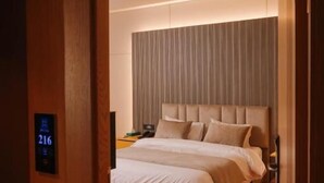 A hotel room with a bed, wooden flooring, a headboard, and a digital display showing room number 216. - Hotel ehden (Ehden)