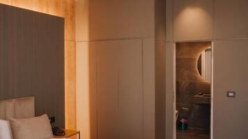 A modern hotel room with a large bed, a wardrobe, and a bathroom visible through an open door.