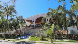 Un hotel de fachada de piedra, palmeras y un letrero que dice "SANDOS".