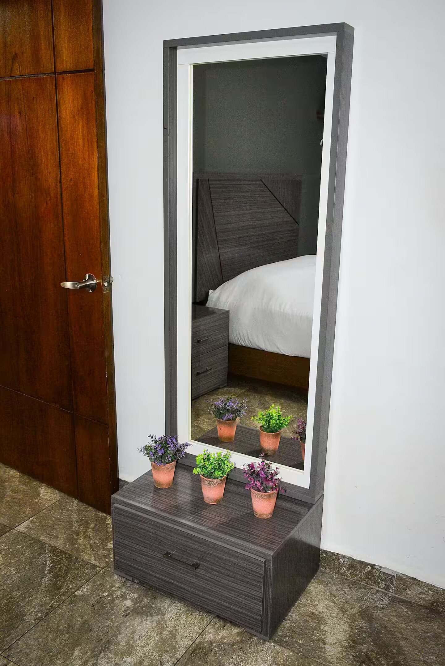 Un miroir avec une porte en bois et un lit qui se reflète dans le miroir.
