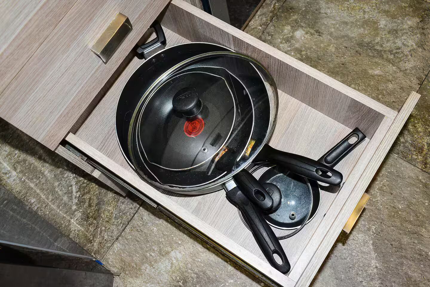 A kitchen drawer with a frying pan and a spatula.