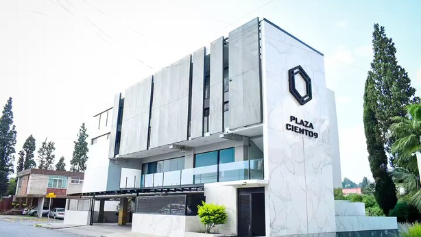 Un edificio moderno con un cartello che riporta la scritta "PLAZA CIENTO".