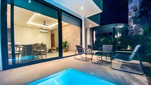 Ein moderner Poolbereich im Freien mit Liegestühlen, einem Essbereich und Blick ins Innere.
