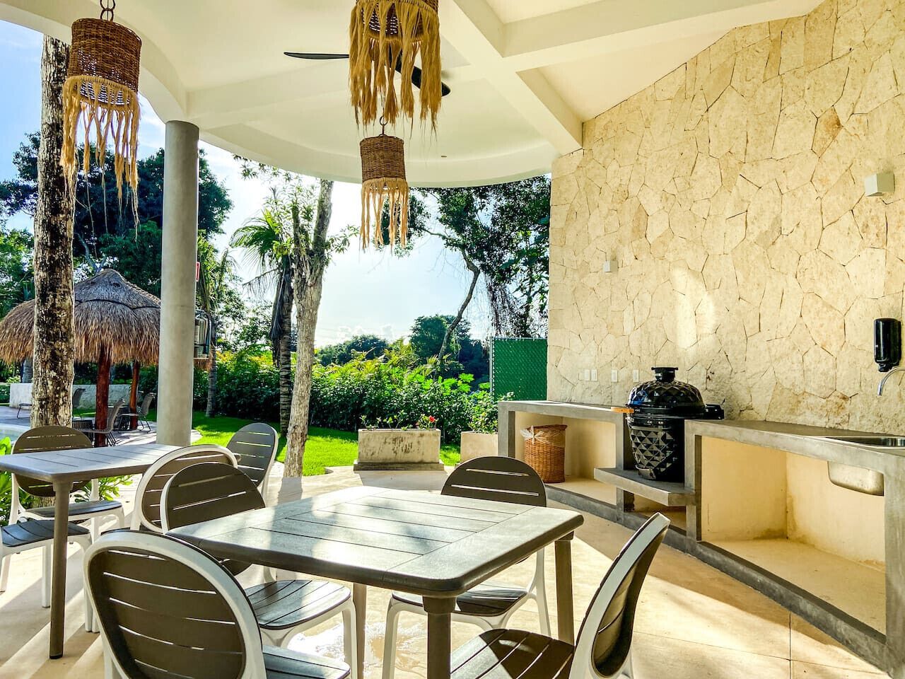 An outdoor dining area with tables and chairs, a stone wall, and a grill station.