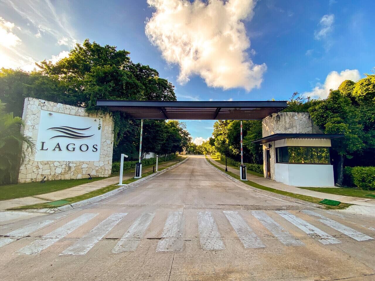 A road leading to a building with a stone wall and a sign that reads 'LAGOS.'