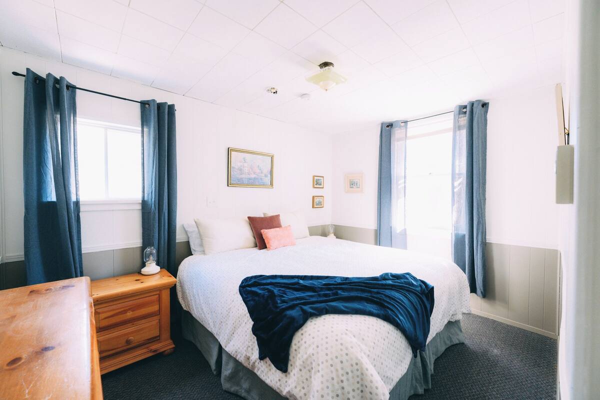 A bedroom with a bed, nightstand, and a wooden table.