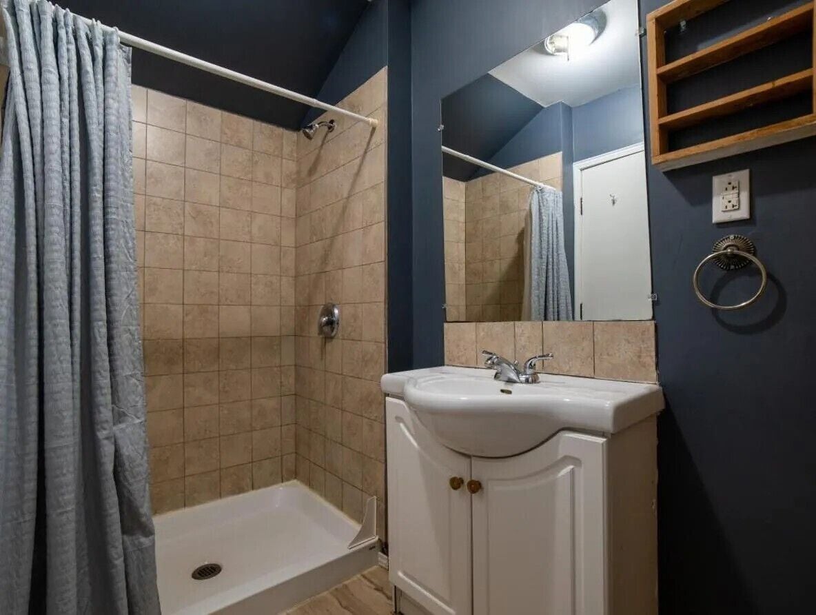Un baño con ducha, lavabo y espejo.